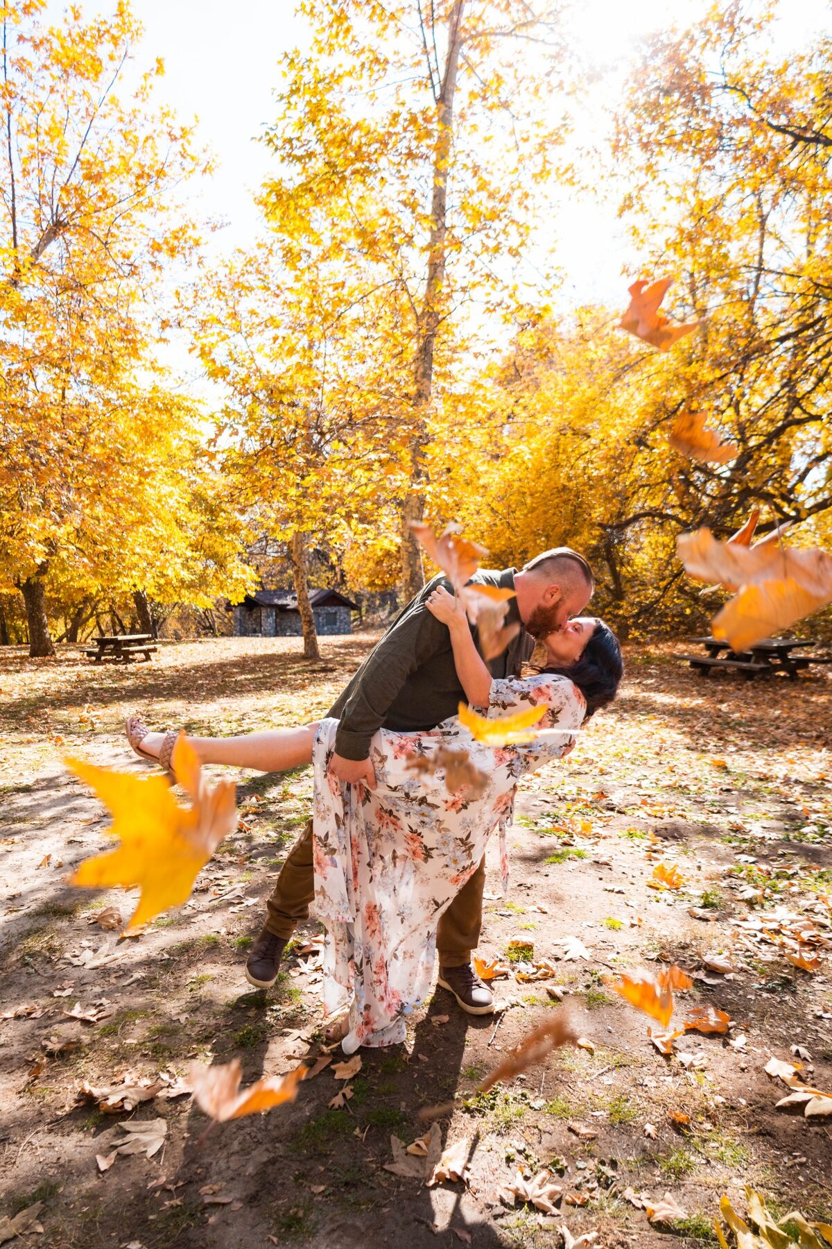 Couple kissing beneath falling autumn leaves