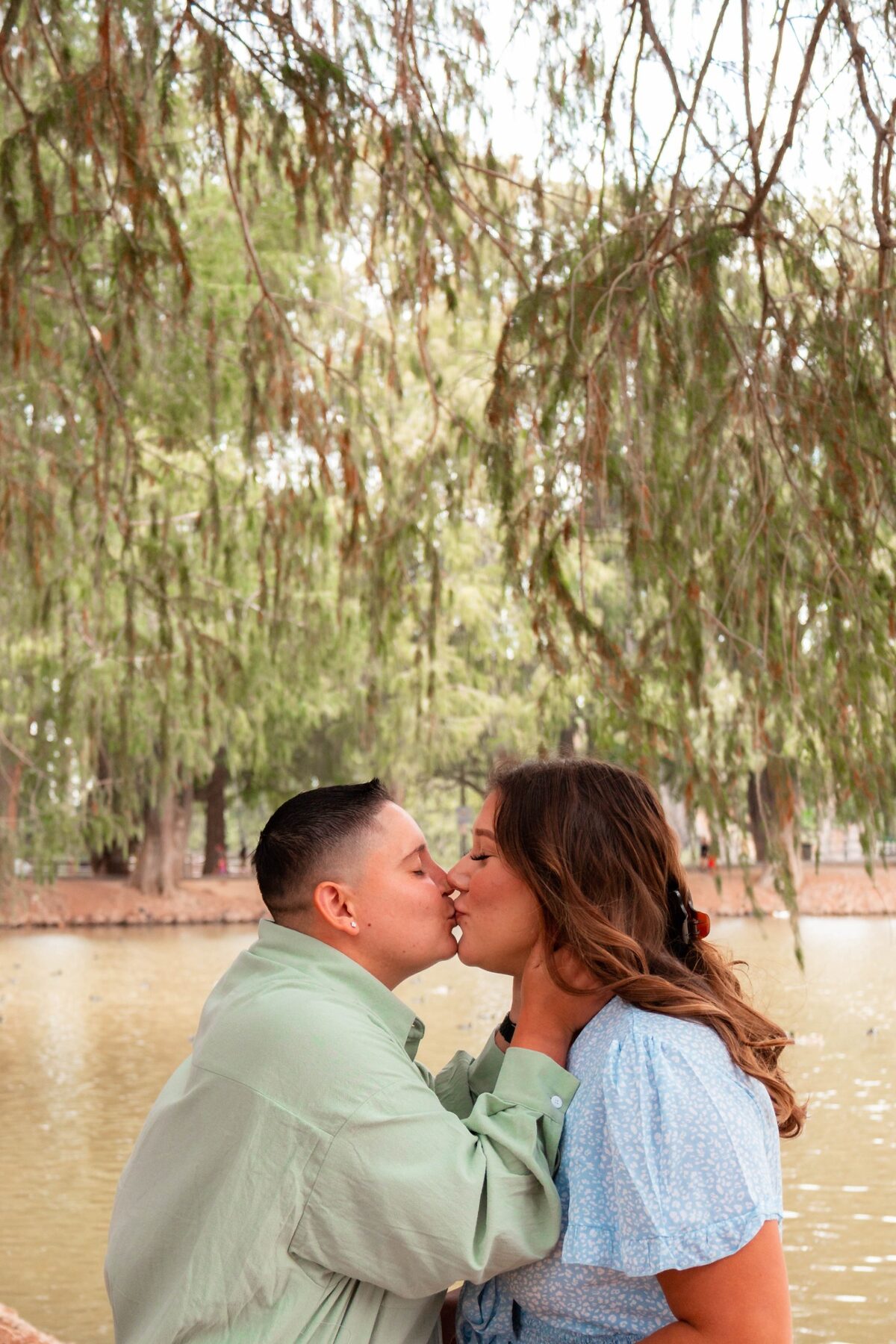 Couple kissing beneath a lakeside tree