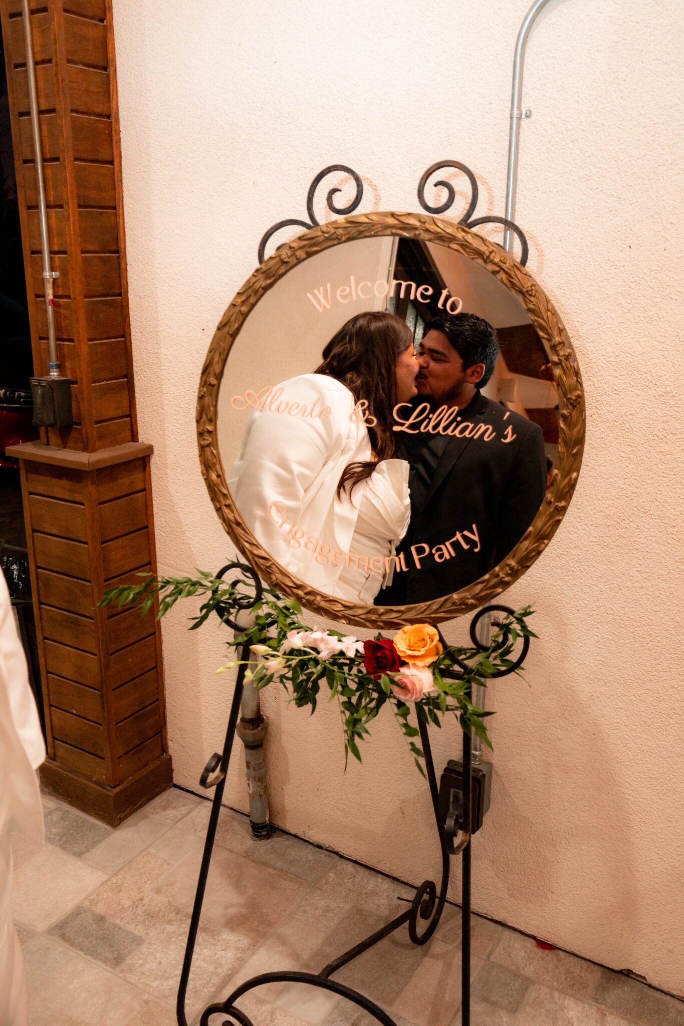 Engaged couple kissing in a mirror at their party