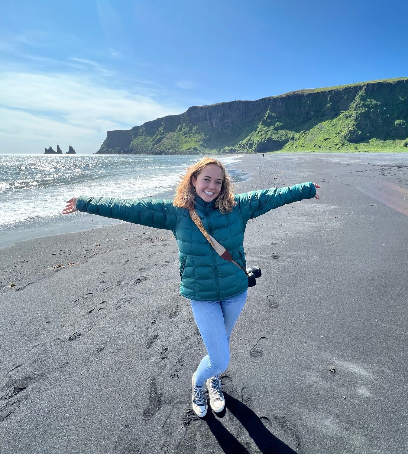 Jade West exploring a black-sand beach with her camera